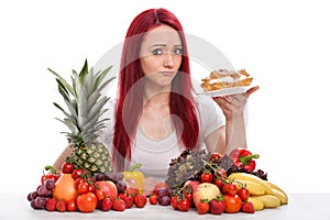 Young woman thinks about eating a cake rather than fruits or vegetables