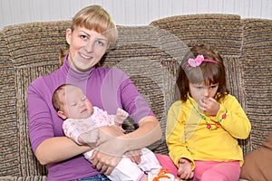 The young woman with the three-year-old daughter and the baby sis on a sofa