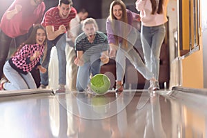 Young woman throwing ball and spending time with friends in bowling