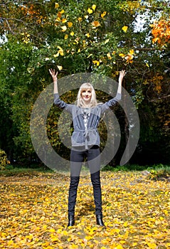 Young woman throwing leaves in the air