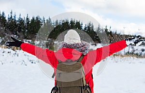 Young woman throwing snow into the air on a sunny winter day, back view. Feeling of freedom and fun.