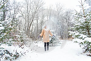 Young woman throwing snow in the air at sunny winter day, she is happy and fun.