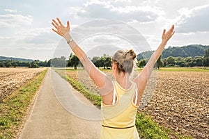 Young woman throwing up her ams at the start of rural road photo