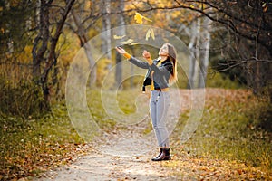 Young woman throws autumn yellow leaves in park. Concept new life