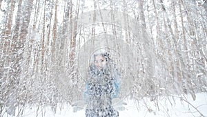 Young woman throws snow up with a nice smile in the winter forest