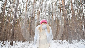 Young woman throws snow up with a nice smile in the winter forest
