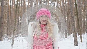 Young woman throws snow up with a nice smile in the winter forest