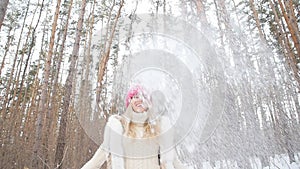 Young woman throws snow up with a nice smile in the winter forest