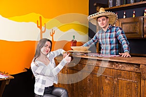 Young woman with thumbs up sitting at the bar counter next to th