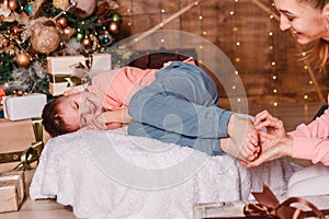 Young woman tickles the bare feet of a sleeping child. Christmas and gifts