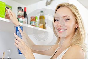 Young woman tiding up kitchen cupboards