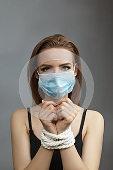 Young woman with tied hands in a medical mask