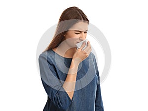 Young woman with tissue suffering from runny nose on white background