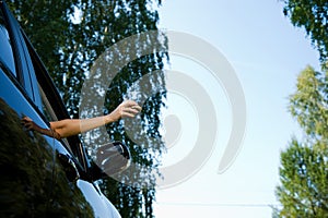 A young woman is about to throw a crumpled piece of paper or packaging from a sandwich into an open car window. View