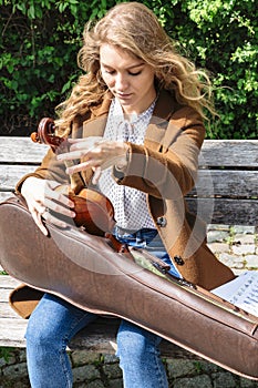 Young woman tooks violin from case and sets it up