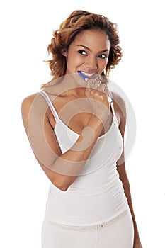 Young woman with tooth brush in her mouth.