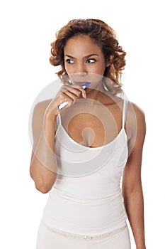 Young woman with tooth brush in her mouth looks to the side.