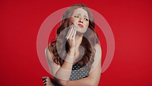 Young woman with tooth pain on red studio background. Toothache, dental problems