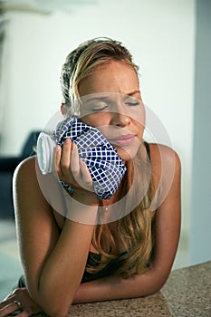 Young woman with toothache holding ice bag on mouth