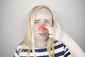 A young woman touches her nose, which is very painful. Medical care concept for difficulty breathing, clogged nasal passages and