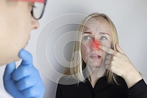 A young woman touches her nose, which is very painful. Medical care concept for difficulty breathing, clogged nasal passages and