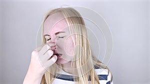 A young woman touches her nose, which is very painful. Medical care concept for difficulty breathing, clogged nasal passages and f