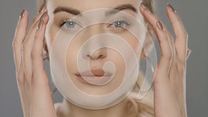 Young woman touching face skin in studio. Fashion model correcting makeup