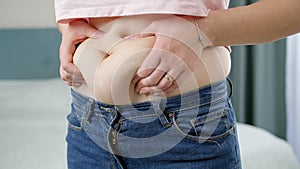 Young woman touching her big belly and holding fat folds. Concept of excessive weight, obese female, dieting and