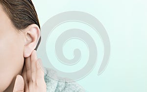 Young woman touching her ear on a blue background