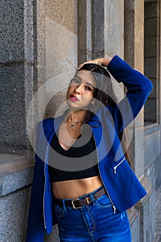 Young woman touching her hair leaning against  wall