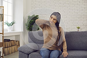 Young woman touching her neck, suffering from pain, stiff joints and tensed muscles