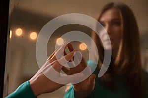 Young woman touching her own reflection in a mirror