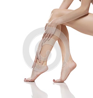 Young woman touching her smooth long legs, and putting on moisturizer after shaving her legs
