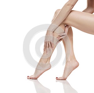 Young woman touching her smooth long legs, and putting on moisturizer after shaving her legs