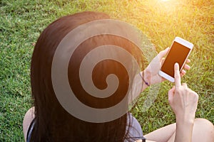 Young woman touching smartphone on green grass