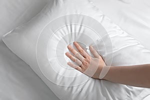 Young woman touching soft white pillow