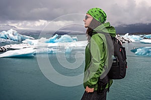A young woman tourist 30-35 years old admires the frozen sea on the coast of Iceland, a wild cold beach, blocks of ice.