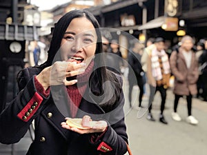 Young woman tourist enjoy eating Japanese street food Hida Beef Sushi and cracker at Takayama, Japan