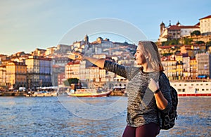 Young woman tourist enjoying beautiful landscape view on the old town Ribeira historical quarter and river Duoro during the