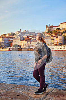 Young woman tourist enjoying beautiful landscape view on the old town Ribeira historical quarter and river Duoro during the