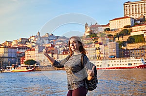 Young woman tourist enjoying beautiful landscape view on the old town Ribeira historical quarter and river Duoro during the