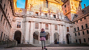 A young woman tourist with her back in front of the Basilica at El Escorial in Spain