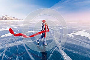 Young woman tourist on ice skates and with long red scarf on frozen lake Baikal. Concept Amazing winter photography