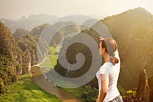 Woman tourist looking far away and enjoying valley and hills view from top of a mountain photo