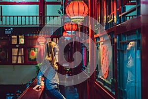 Young woman tourist looks at the Chinese traditional lanterns. Chinese New Year. Travel to China concept