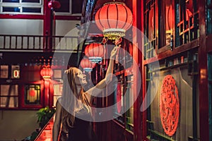 Young woman tourist looks at the Chinese traditional lanterns. Chinese New Year. Travel to China concept