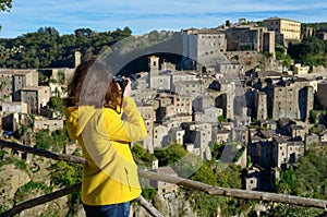 Woman tourist making photo of medieval tuff Sorano town in Italy photo