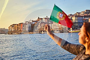 Young woman tourist with portuguese flag enjoying beautiful landscape view on the old town Ribeira historical quarter and river