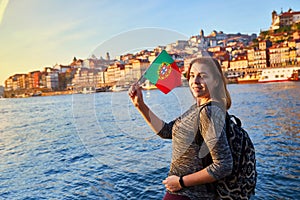 Young woman tourist with portuguese flag enjoying beautiful landscape view on the old town Ribeira historical quarter and river