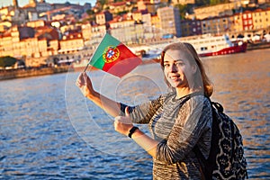 Young woman tourist with portuguese flag enjoying beautiful landscape view on the old town Ribeira historical quarter and river